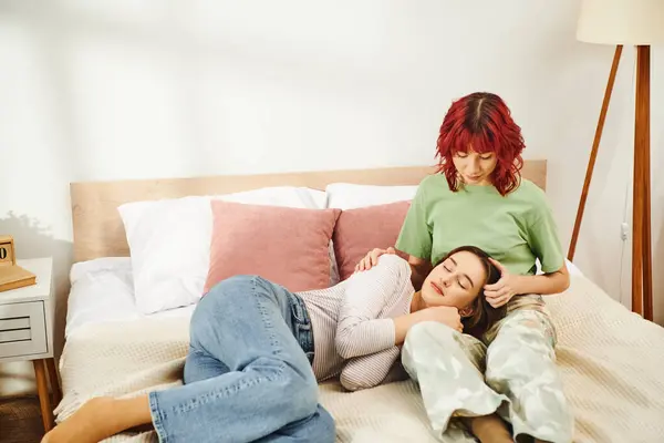 Joven pareja lesbiana compartiendo un hermoso momento, mujer acostada en vueltas sobre su novia en el dormitorio - foto de stock