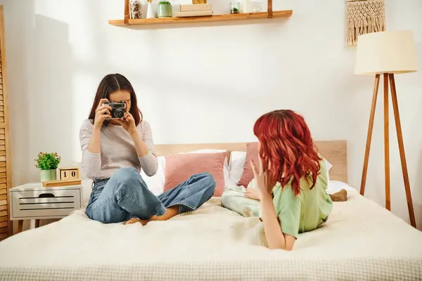 Candid home photo session of lesbian woman taking photo on retro camera of her girlfriend on bed — Stock Photo