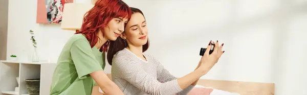 Баннер домашней фотосессии счастливой молодой лесбийской пары, делающей селфи на ретро-камеру в спальне — стоковое фото