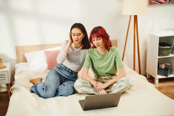 Felice giovane coppia lesbica in abbigliamento casual guardare film online insieme sul computer portatile in camera da letto — Foto stock