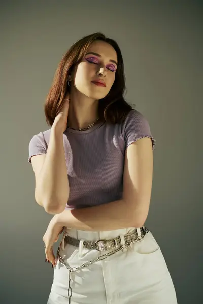 Смелый макияж стильный ген z девушка в 20 лет позирует в фиолетовой футболке и белых джинсах, с закрытыми глазами — стоковое фото