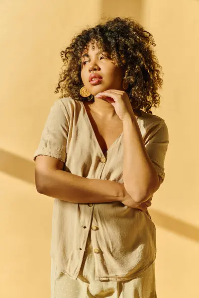 A beautiful young African American woman with curly hair poses in a summer dress in a studio setting. — Stock Photo
