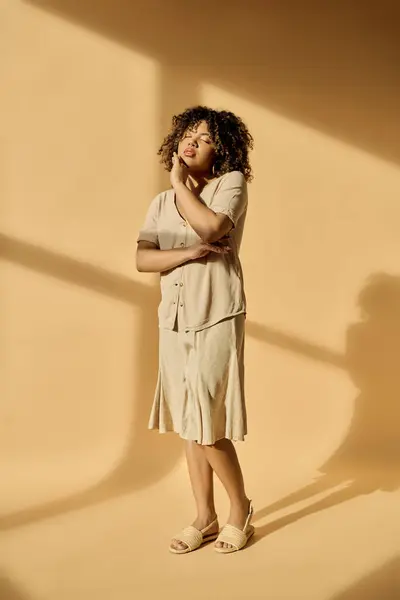 Una bella donna afroamericana con i capelli ricci si trova in una stanza, le braccia incrociate in una posa premurosa. — Foto stock