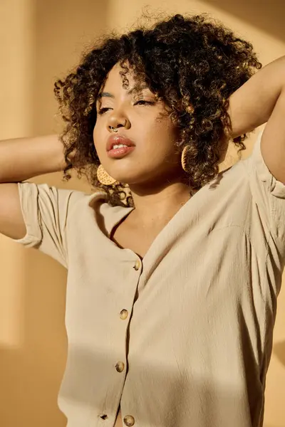 A beautiful young African American woman with curly hair wearing a summer dress poses confidently for a photoshoot in a studio. — Stock Photo