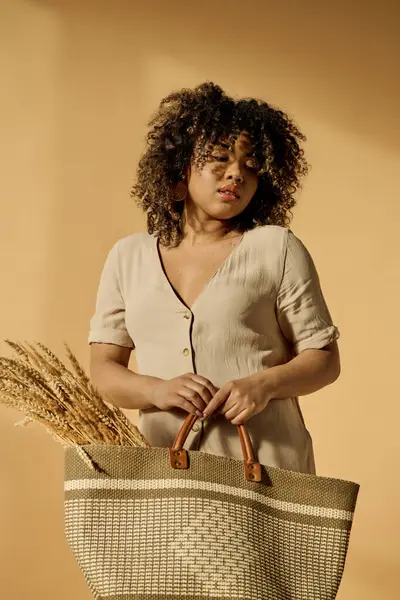 A beautiful young African American woman with curly hair holding a basket with a handle in a studio setting. — Stock Photo