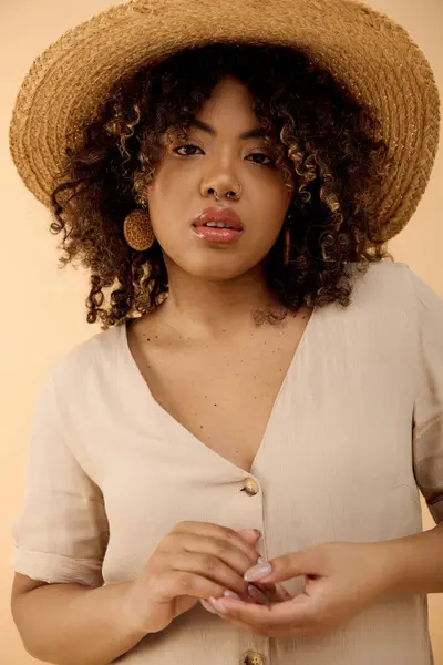 A beautiful young African American woman with curly hair wearing a straw hat and a white shirt exudes elegance in a studio setting. — Stock Photo