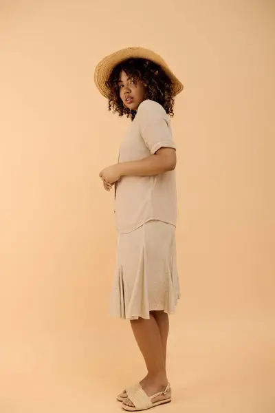 Une belle jeune femme afro-américaine aux cheveux bouclés et à la robe d'été posant élégamment dans un décor de studio. — Photo de stock