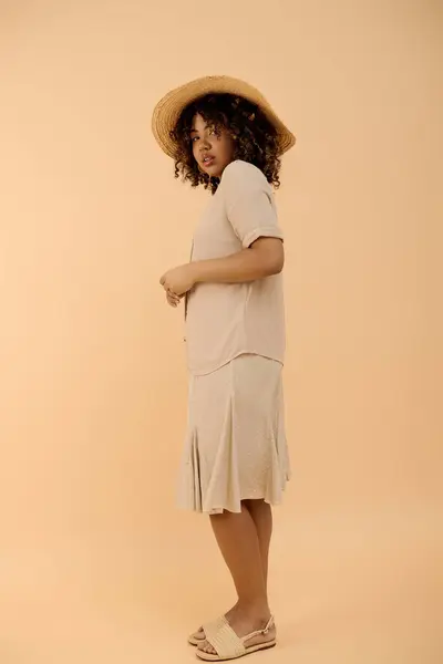 A beautiful young African American woman with curly hair and a summer dress elegantly posing in a studio setting. — Stock Photo