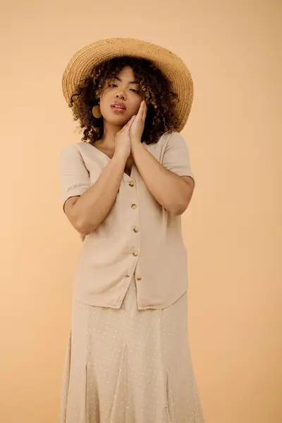 A beautiful young African American woman with curly hair wearing a summer dress and hat in a studio setting. — Stock Photo