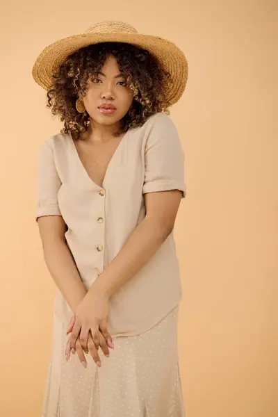 A beautiful young African American woman with curly hair elegantly dressed in a summer dress and hat in a studio setting. — Stock Photo