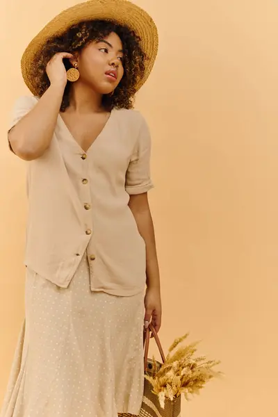 Una hermosa joven afroamericana con el pelo rizado con un vestido de verano y sombrero - foto de stock