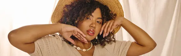 Young African American woman with curly hair in a summer dress, elegant in a straw hat covering her face. — Stock Photo