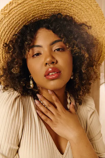 A beautiful young African American woman with curly hair, wearing a straw hat, gazes serenely with hands on her chest. — Stock Photo