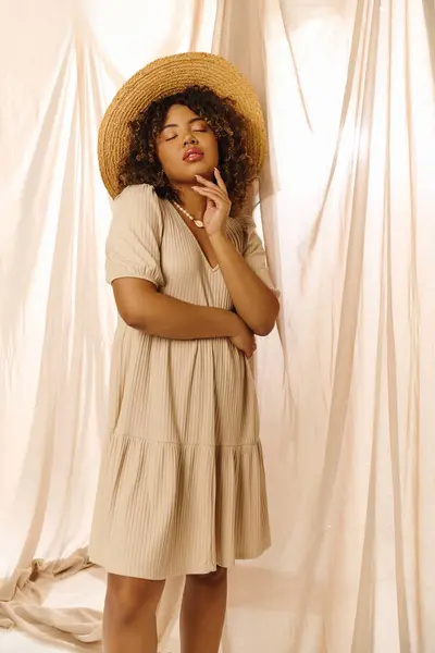 Eine schöne junge Afroamerikanerin mit lockigem Haar posiert für ein Foto mit Strohhut in einem Studio-Setting. — Stockfoto