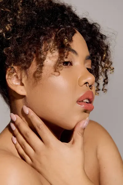 Eine junge Afroamerikanerin mit lockigem Haar, die zärtlich ihre Hände auf ihre Brust legt und Selbstfürsorge und Schönheit zur Schau stellt. — Stockfoto