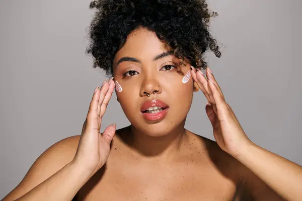 Una giovane donna afroamericana con i capelli ricci che si tiene le mani fino al viso in una posa premurosa. — Foto stock