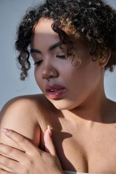 Eine atemberaubende junge Afroamerikanerin mit lockigem Haar, das natürliche Schönheit in einem Studio-Setting ausstrahlt. — Stockfoto
