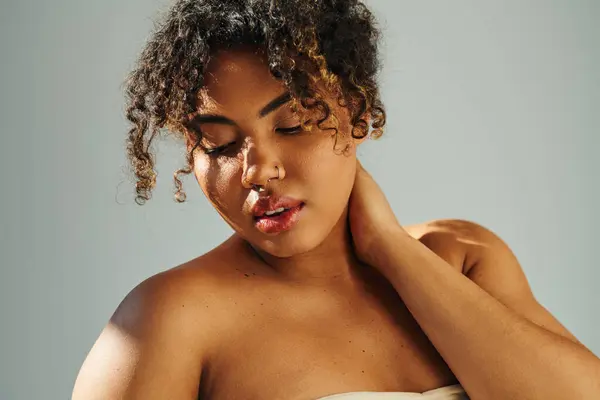 Elegante donna afroamericana in abito senza spalline massaggiare il collo teneramente. — Foto stock