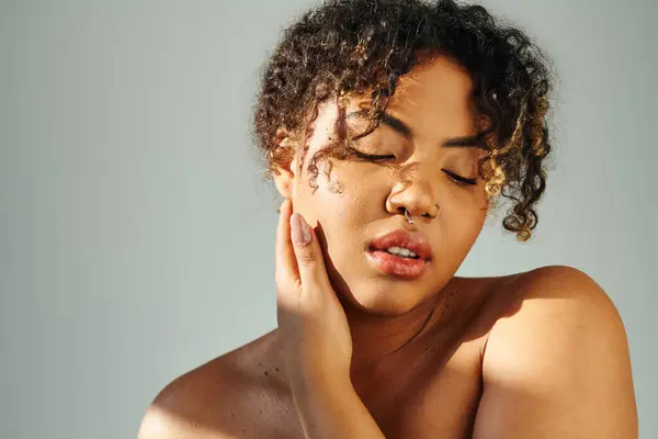 Una donna afroamericana si copre con grazia il viso con la mano. — Foto stock