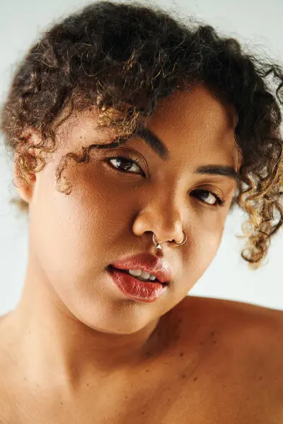 Close-up de mulher afro-americana com anel de nariz elegante, impressionante pose no fundo vibrante. — Fotografia de Stock