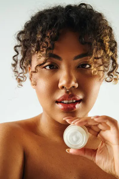 Attractive African American woman showcasing cream jar. — Stock Photo