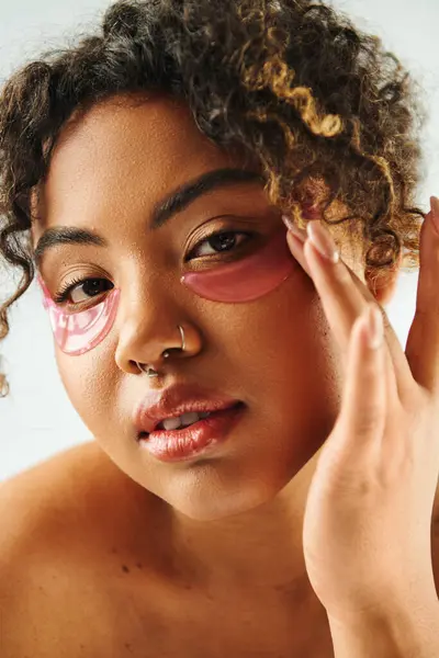 A close-up view of a beautiful African American woman showcasing eye patches on a vibrant backdrop. - foto de stock