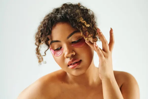 Beautiful African American woman showcasing eye patches on a vibrant backdrop. — Stock Photo