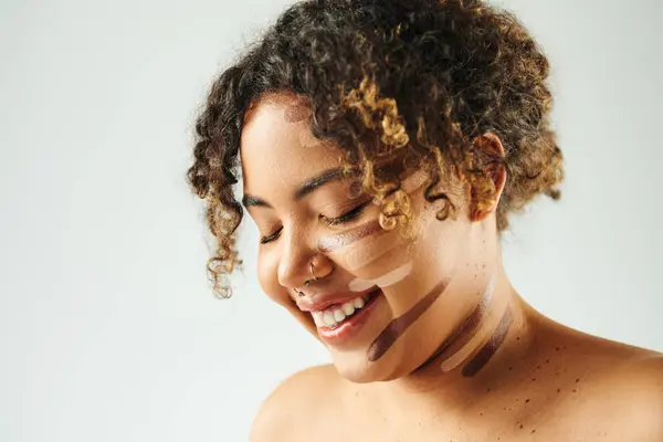 Attraente donna afroamericana con fondazione su pose viso sullo sfondo vibrante. — Foto stock