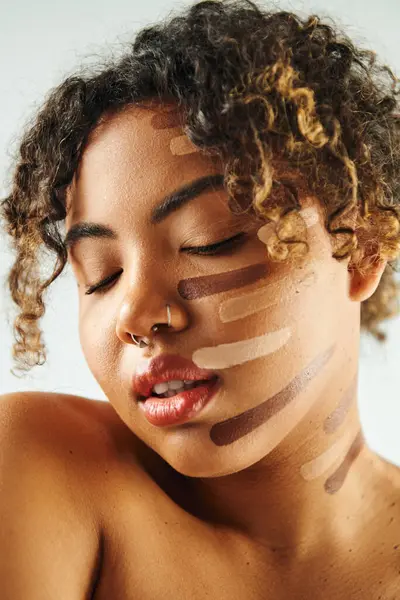 Hübsche Afroamerikanerin mit Fundament im Gesicht posiert vor lebendiger Kulisse. — Stockfoto