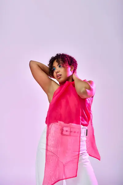 Postura activa de una mujer afroamericana impresionante en un top rosa y pantalones blancos. - foto de stock