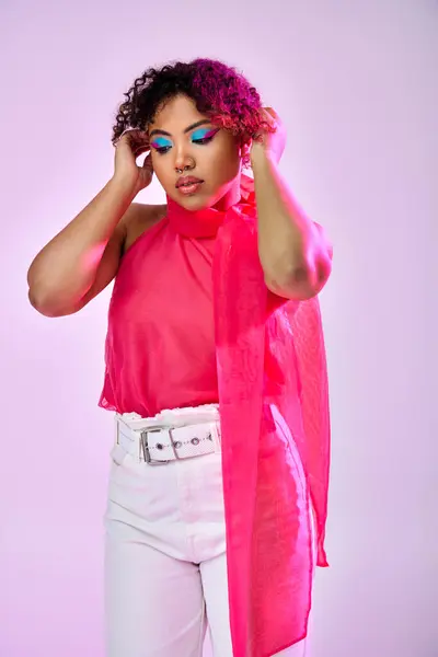 A beautiful African American woman actively posing in a pink shirt and white pants on a vibrant backdrop. — Stock Photo