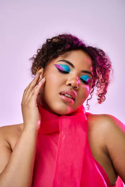 African American woman wearing a pink dress and bold makeup strikes a dynamic pose against a vibrant backdrop. — Stock Photo