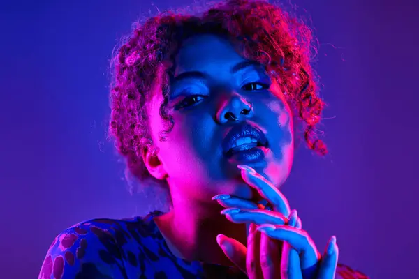 A striking African American woman poses with vibrant curly hair and bold blue makeup. — Stock Photo