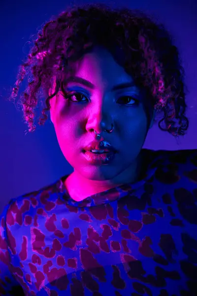 African American woman with curly hair in leopard print shirt posing on vibrant backdrop. — Stock Photo
