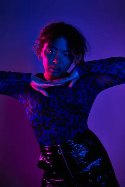 Uma mulher afro-americana elegante posando ativamente em uma camisa de impressão de leopardo e saia de couro. — Fotografia de Stock