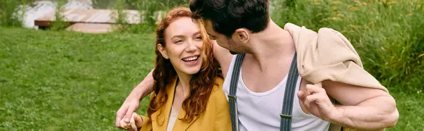 A man carries a woman on his back through a serene green park on a romantic date, surrounded by natures beauty. — Stock Photo