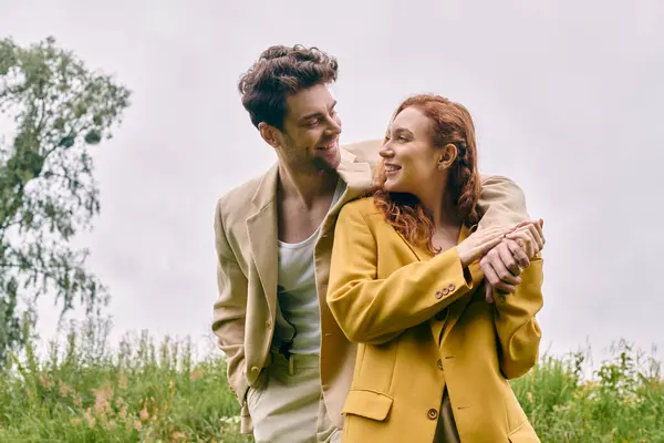 Un uomo e una donna stanno insieme in un campo lussureggiante, godendo di un sereno appuntamento romantico nel cuore della natura bellezza. — Foto stock