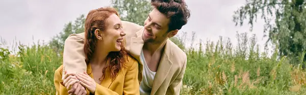 Um homem ternamente mantém uma mulher em um campo verde exuberante, compartilhando um momento de afeto e conexão em sua data romântica. — Fotografia de Stock