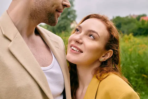 Мужчина и женщина, воплощающие элегантность, стоят бок о бок в пышном зеленом парке, создавая мирную и романтическую сцену. — стоковое фото
