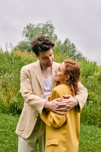 A man and a woman share a tender embrace in a lush green field, surrounded by natures beauty. — Stock Photo