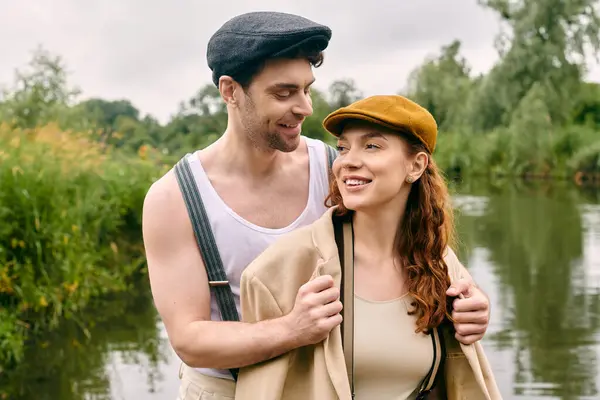 A man and woman standing by the river, enjoying a romantic date in a beautiful green park setting. — Stock Photo
