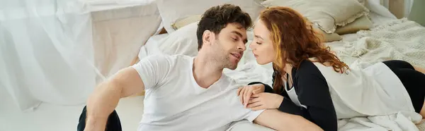 A man and a woman sit closely together on a bed, sharing a quiet moment in their bedroom. — Stock Photo