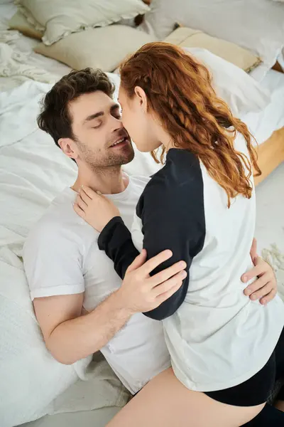 Un homme et une femme se blottissent sur un lit douillet dans un moment tendre de convivialité et d'intimité. — Photo de stock