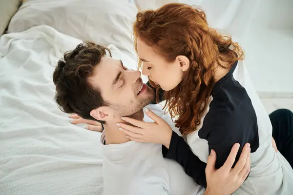 Un homme et une femme s'embrassent paisiblement alors qu'ils sont allongés sur un lit dans un cadre de chambre. — Photo de stock