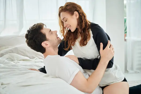 A couple sit closely together on a bed, engrossed in conversation and enjoying each others company in a cozy bedroom setting. — Stock Photo