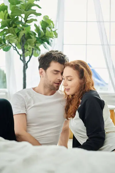 A man and woman are sitting closely together on a comfortable bed, enjoying each others company — Stock Photo