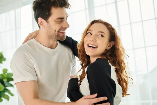 A man tenderly holds a woman in his arms, creating a moment of intimacy and comfort between the beautiful couple in a cozy bedroom. — Stock Photo