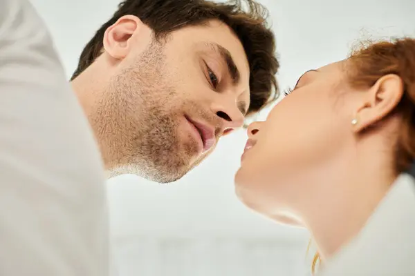 Um homem e uma mulher apaixonadamente se beijam, compartilhando um momento terno de amor em um ambiente aconchegante no quarto. — Fotografia de Stock