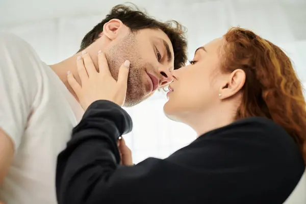 A man and a woman sharing a tender kiss, expressing intimacy and love in a bedroom setting. — Stock Photo