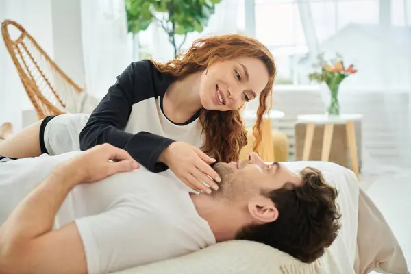 A man laying on top of a woman on a cozy bed, sharing an intimate moment together. — Stock Photo